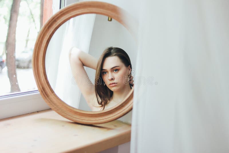 Jeune beau long mannequin sensuel de fille de cheveux devant le miroir rond, foyer mou images stock Jeune beau long mannequin sensuel de fille de cheveux devant le miroir rond, foyer mou images stock