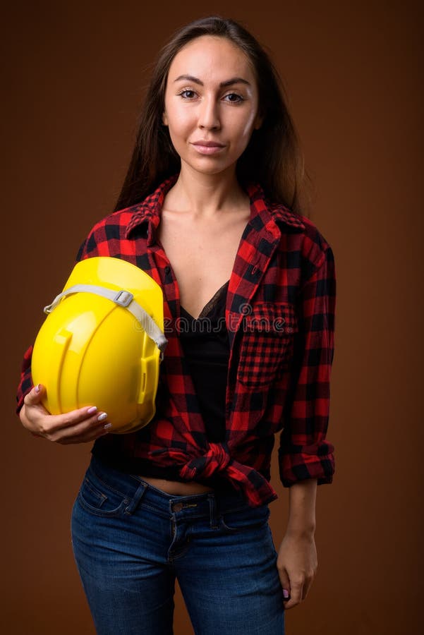 Jeune beau travailleur de la construction de femme contre le backgrou brun image libre de droits Jeune beau travailleur de la construction de femme contre le backgrou brun image libre de droits