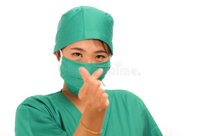 Isolated portrait of young beautiful and happy Asian Chinese medicine doctor woman or hospital nurse in medical hat face mask and scrub doing fingers love sign smiling cheerful and positive in health care. Isolated portrait of young beautiful and happy Asian Chinese medicine doctor woman or hospital nurse in medical hat face mask and scrub doing fingers love sign smiling cheerful and positive in health care