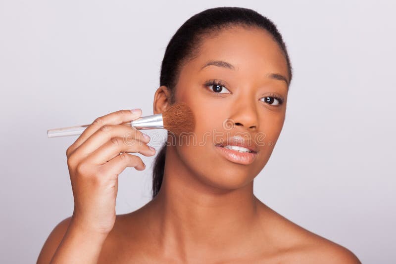 Jeune belle femme africaine appliquant le maquillage - personnes de race noire images stock Jeune belle femme africaine appliquant le maquillage - personnes de race noire images stock