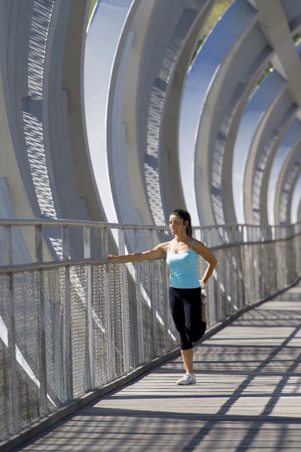 Jeune belle femme de sport sportif s'étirant après pont moderne de ville en métal de croisement courant image libre de droits