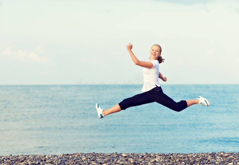 Jeune belle femme heureuse sautant à la plage sur la mer images libres de droits Jeune belle femme heureuse sautant à la plage sur la mer images libres de droits