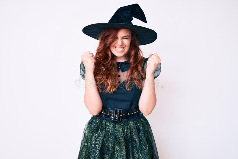 Young beautiful woman wearing witch halloween costume excited for success with arms raised and eyes closed celebrating victory smiling. winner concept. Young beautiful woman wearing witch halloween costume excited for success with arms raised and eyes closed celebrating victory smiling. winner concept