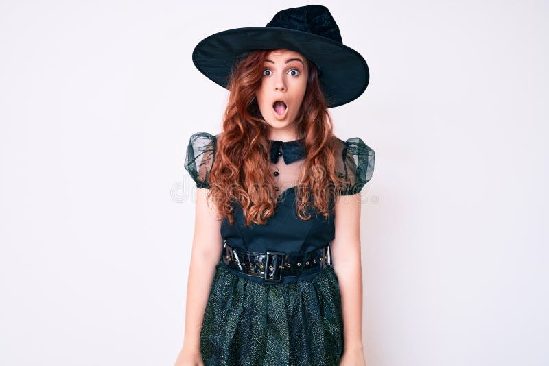 Young beautiful woman wearing witch halloween costume afraid and shocked with surprise and amazed expression, fear and excited face. Young beautiful woman wearing witch halloween costume afraid and shocked with surprise and amazed expression, fear and excited face