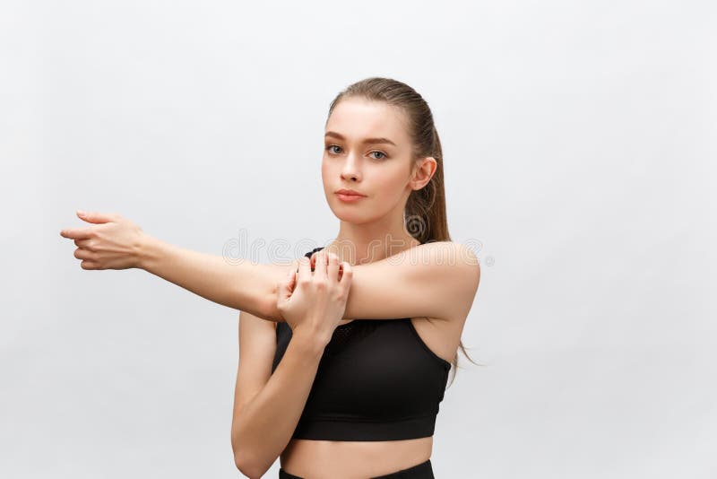 Jeune belle femme sportive étirant des bras de côté D'isolement au-dessus du fond blanc images stock Jeune belle femme sportive étirant des bras de côté D'isolement au-dessus du fond blanc images stock