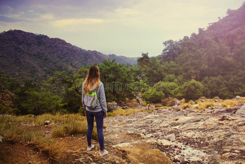 Jeune belle fille dans la chemise de hoodie et le sac à dos touristique regardant sur le paysage étonnant de la montagne de Hemer images stock Jeune belle fille dans la chemise de hoodie et le sac à dos touristique regardant sur le paysage étonnant de la montagne de Hemer images stock