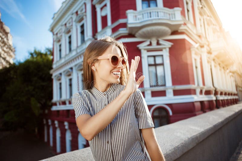 Jeune belle fille gaie dans des lunettes de soleil marchant autour de la ville, souriant Fond extérieur photo libre de droits Jeune belle fille gaie dans des lunettes de soleil marchant autour de la ville, souriant Fond extérieur photo libre de droits