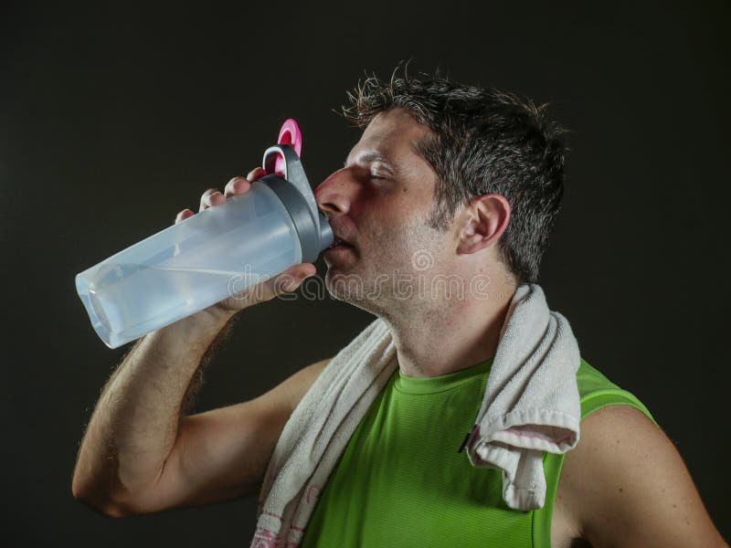 Jeune bouteille potable en sueur attrayante et d'ajustement de sport d'homme de retenue d'eau refroidissant après séance d'entraî photographie stock libre de droits Jeune bouteille potable en sueur attrayante et d'ajustement de sport d'homme de retenue d'eau refroidissant après séance d'entraî photographie stock libre de droits