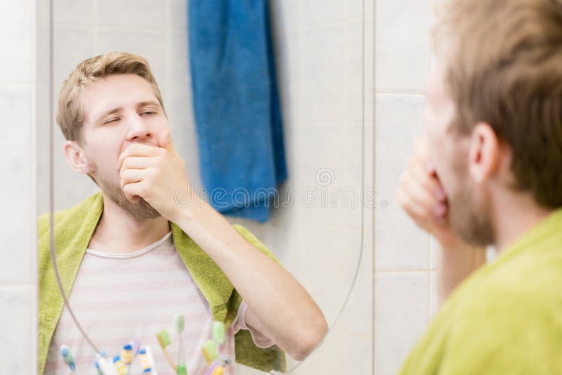 Jeune bâillement barbu d'homme devant le miroir dans la salle de bains photos libres de droits Jeune bâillement barbu d'homme devant le miroir dans la salle de bains photos libres de droits