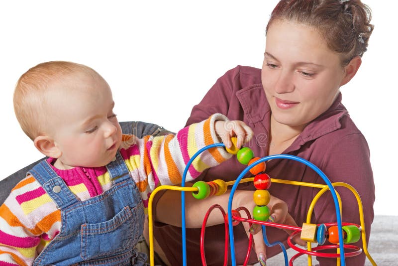 Baby with motor activity development delay being stimulated to develop muscle coordination and movement on a bead maze watched by a devoted mother. Baby with motor activity development delay being stimulated to develop muscle coordination and movement on a bead maze watched by a devoted mother