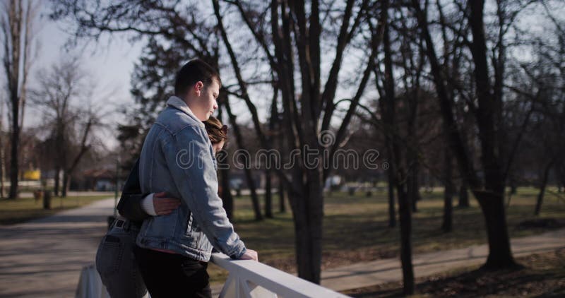 Jeune couple amoureux Embrassez-vous sur un pont dans un parc serein banque de vidéos