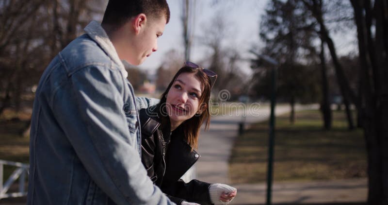 Jeune couple amoureux qui parle et rit dans un parc pendant une journée ensoleillée banque de vidéos