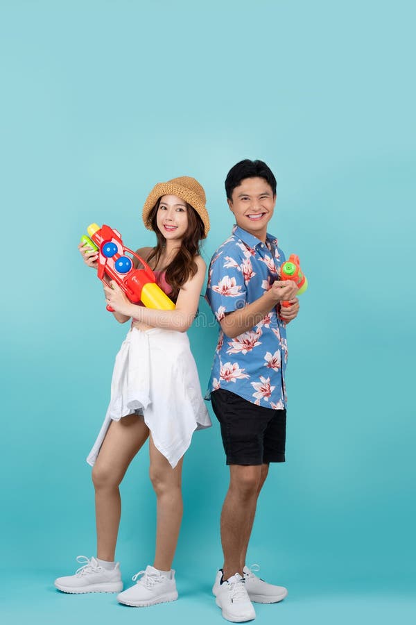 Jeune couple asiatique en tenue d'été avec canons à eau en studio bleu. festival songkran photographie stock