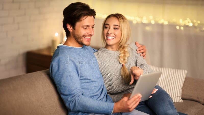 Jeune couple choisissant un film sur tablette reposant ensemble à la maison photographie stock libre de droits