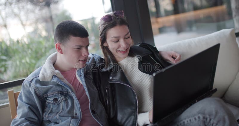 Jeune couple naviguant en ligne ensemble sur ordinateur portable dans un café Partager un moment spécial banque de vidéos