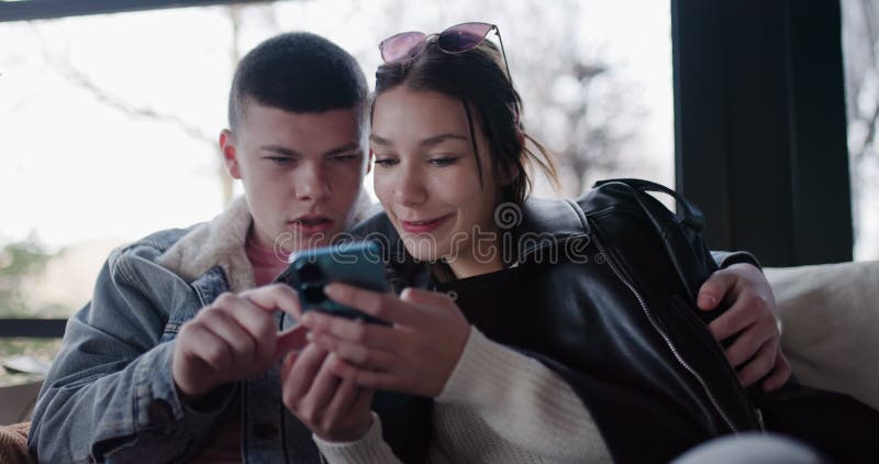 Jeune couple naviguant sur les médias sociaux ou faire du shopping sur Smartphone au Café. Joyeux adolescents utilisant la cellule clips vidéos