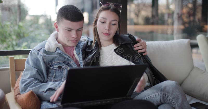 Jeune couple naviguant sur ordinateur portable dans le café partage l'affection et le bonheur banque de vidéos