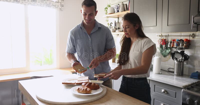Jeune couple positif préparer le petit déjeuner à la maison cuisine banque de vidéos