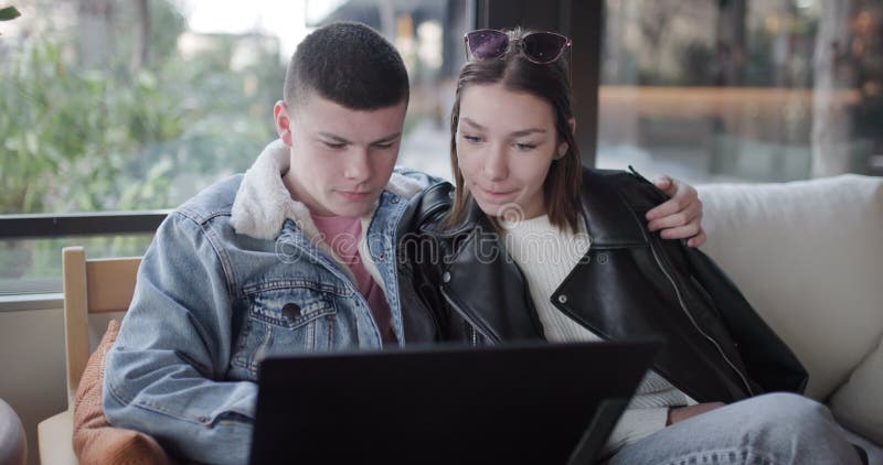 Jeune couple souriant et parlant en utilisant un ordinateur portable sur un canapé : Technologie d'affection et banque de vidéos