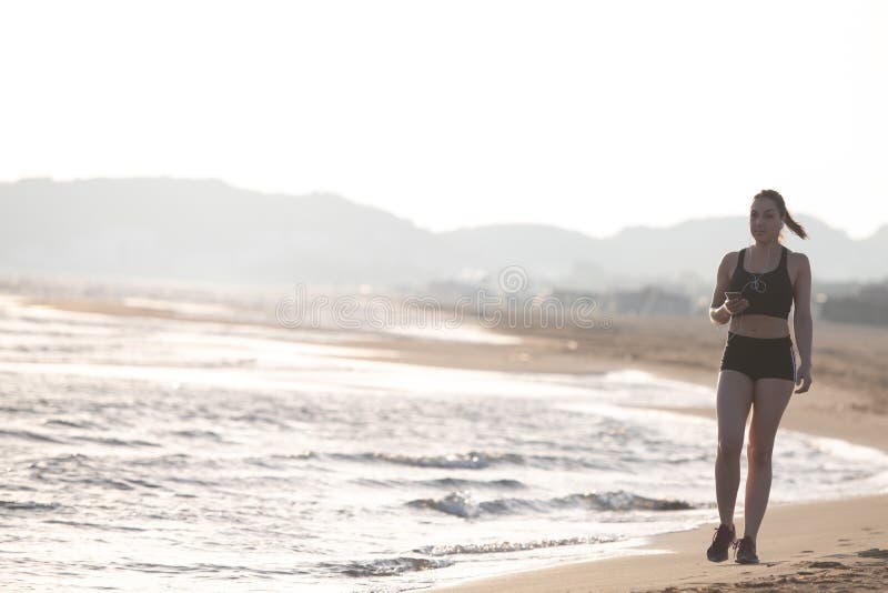 Jeune coureur en bonne santé de femme de forme physique fonctionnant sur le bord de la mer TR de lever de soleil photo libre de droits Jeune coureur en bonne santé de femme de forme physique fonctionnant sur le bord de la mer TR de lever de soleil photo libre de droits