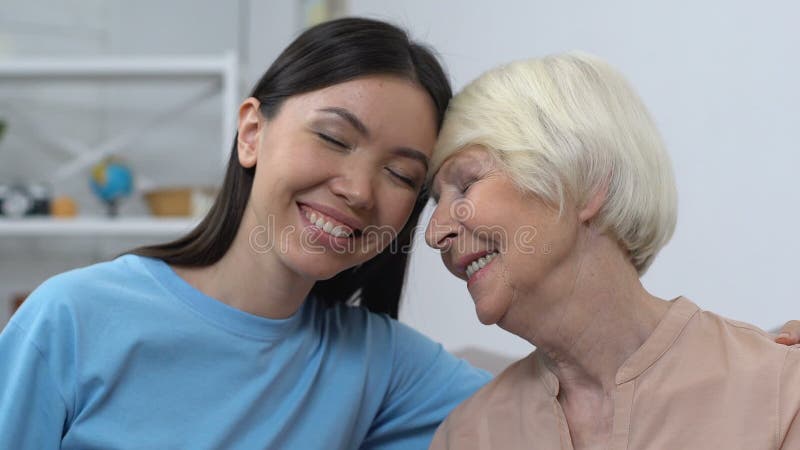Jeune dame amicale souriant à une dame âgée heureuse, aide aux personnes âgées, soins à la famille banque de vidéos