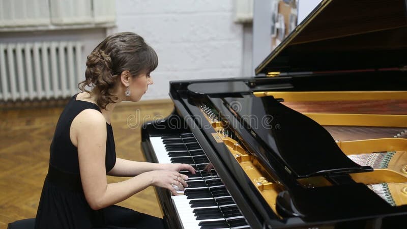 Jeune dame douée heureuse jouant le piano à queue banque de vidéos
