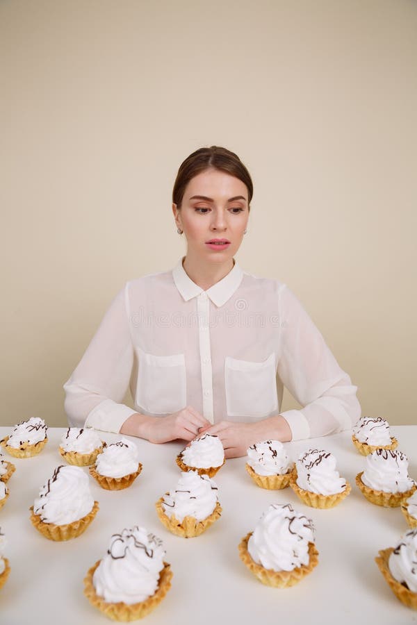 Jeune dame étonnante posant tout en se reposant près du petit gâteau image stock