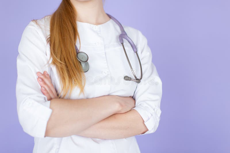 Jeune docteur blond f?minin avec les mains crois?es avec le st?thoscope sur son cou sur le fond pourpre photos stock Jeune docteur blond f?minin avec les mains crois?es avec le st?thoscope sur son cou sur le fond pourpre photos stock