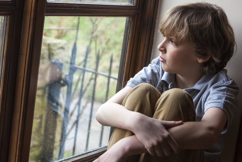Jeune enfant triste de garçon regardant la fenêtre