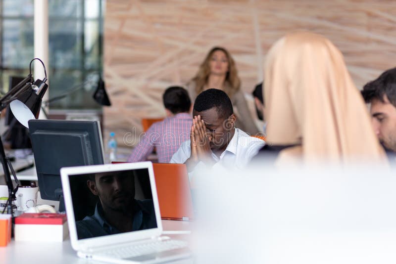 Jeune entrepreneur africain frustrant avec la grimace triste devant son ordinateur portable dans le bureau photographie stock libre de droits Jeune entrepreneur africain frustrant avec la grimace triste devant son ordinateur portable dans le bureau photographie stock libre de droits