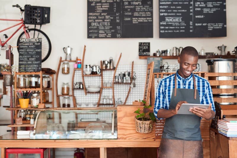 Jeune entrepreneur se tenant en son café utilisant un comprimé numérique