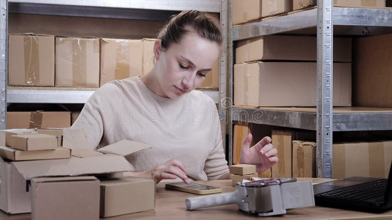 Jeune entrepreneur travaillant à la maison petite entreprise vérifier les commandes internet sur smartphone et préparer des articl banque de vidéos