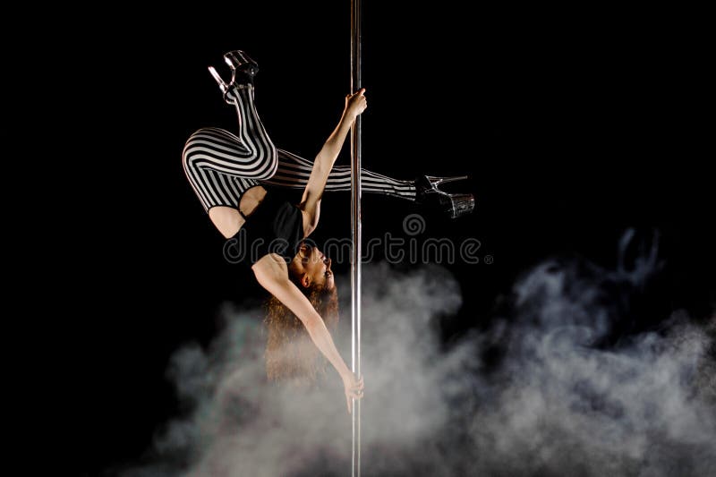 Jeune et belle danse de poteau d'exercices de femme dans la fumée sur un fond noir images libres de droits Jeune et belle danse de poteau d'exercices de femme dans la fumée sur un fond noir images libres de droits