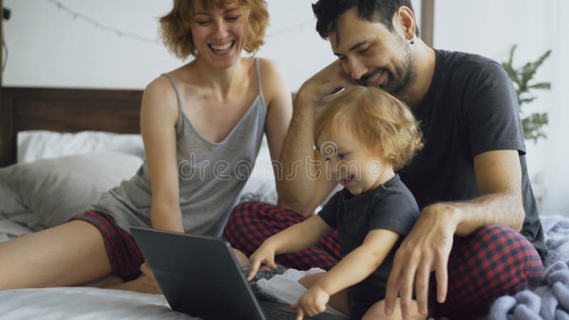 Jeune famille avec la petite fille mignonne jouant avec la fille tandis qu'elle dactylographiant sur l'ordinateur portable se rep image stock Jeune famille avec la petite fille mignonne jouant avec la fille tandis qu'elle dactylographiant sur l'ordinateur portable se rep image stock