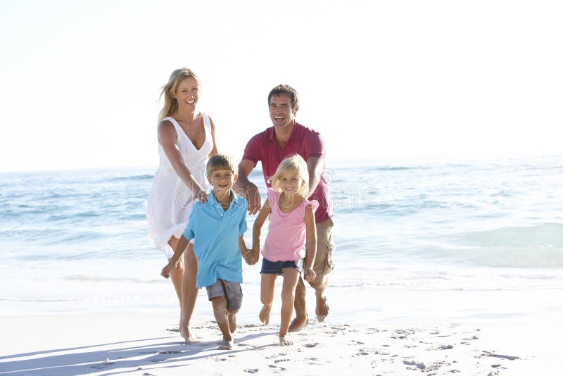 Jeune famille courant le long de Sandy Beach On Holiday photo stock