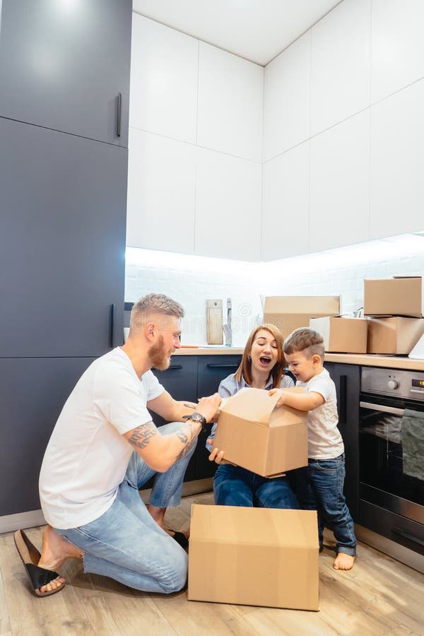 Jeune famille d?ballant des bo?tes dans la nouvelle maison photographie stock libre de droits Jeune famille d?ballant des bo?tes dans la nouvelle maison photographie stock libre de droits