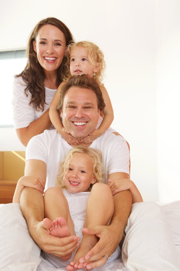 Jeune famille gaie dans le lit à la maison photographie stock Jeune famille gaie dans le lit à la maison photographie stock