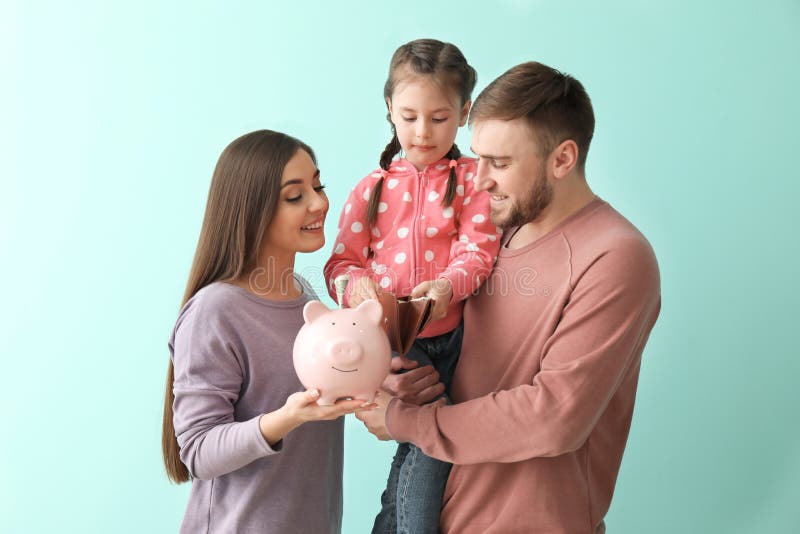 Jeune famille heureuse avec la tirelire, le portefeuille et l'argent sur le fond de couleur photos libres de droits Jeune famille heureuse avec la tirelire, le portefeuille et l'argent sur le fond de couleur photos libres de droits