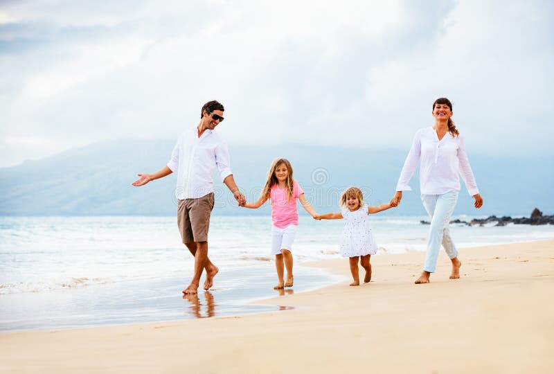 Jeune famille heureuse marchant sur la plage images stock