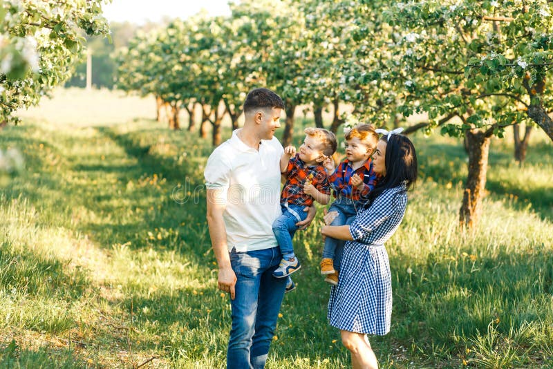 Jeune famille heureuse passant le temps ensemble dehors en nature verte Parents jouant avec des jumeaux Famille du walkng quatre image libre de droits Jeune famille heureuse passant le temps ensemble dehors en nature verte Parents jouant avec des jumeaux Famille du walkng quatre image libre de droits