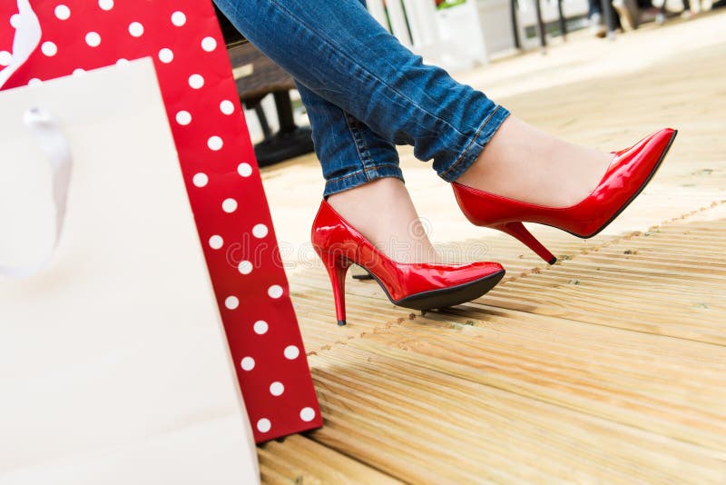 Jeune femelle attirante dans des talons hauts rouges sexy appréciant une coupure après des achats réussis photo libre de droits Jeune femelle attirante dans des talons hauts rouges sexy appréciant une coupure après des achats réussis photo libre de droits