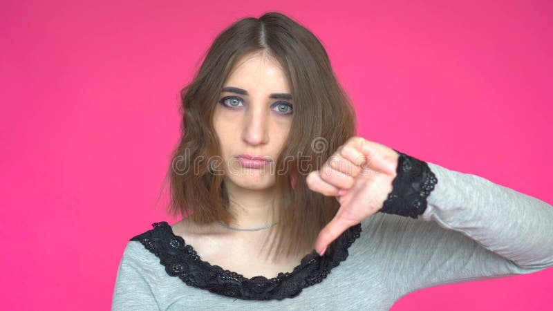 Jeune femme affichant le pouce vers le bas Pose sur le fond rose clips vidéos
