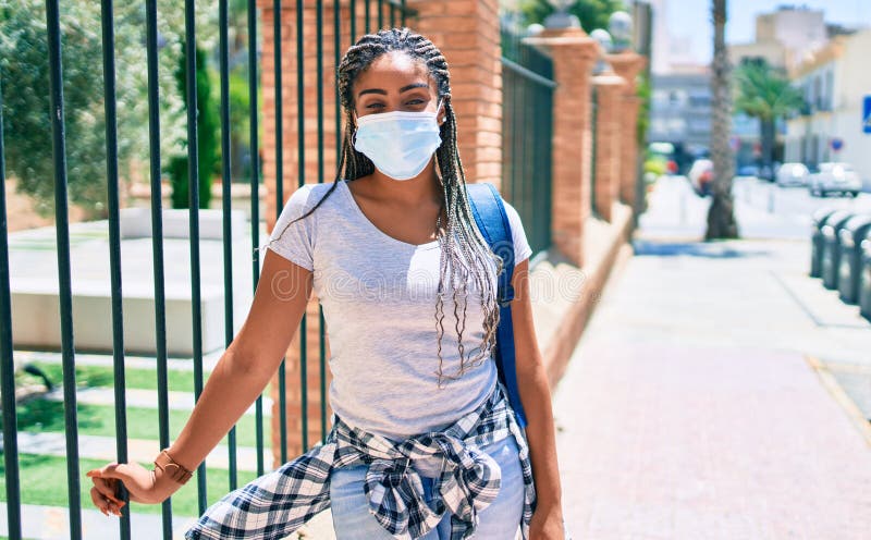 Jeune femme afro-américaine portant un masque de sécurité coronavirus sur le campus universitaire image stock