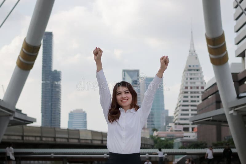 Jeune femme asiatique réussie d'affaires soulevant des mains au fond urbain de ville de bâtiment images libres de droits Jeune femme asiatique réussie d'affaires soulevant des mains au fond urbain de ville de bâtiment images libres de droits