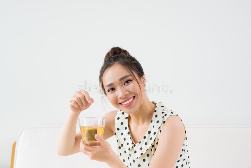 Jeune femme asiatique s'asseyant sur le divan à la maison et le thé potable images libres de droits Jeune femme asiatique s'asseyant sur le divan à la maison et le thé potable images libres de droits