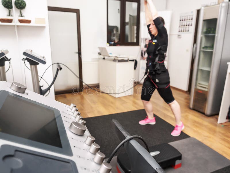 Jeune femme au gymnase par chemin de fer dans un costume avec l'impul électrique images stock Jeune femme au gymnase par chemin de fer dans un costume avec l'impul électrique images stock