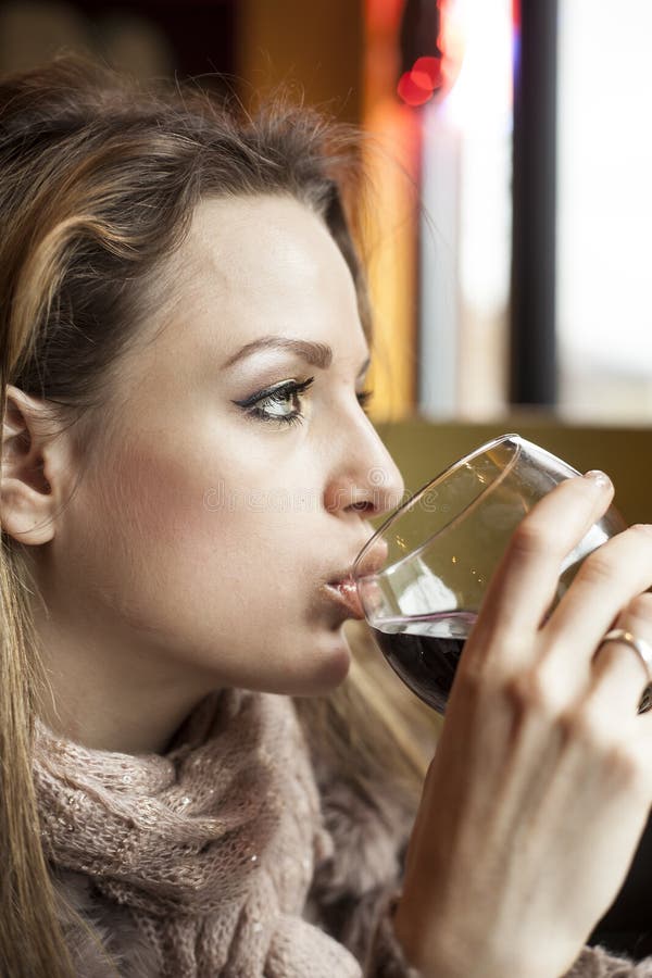 Jeune femme avec de beaux yeux bleus buvant du vin rouge image stock Jeune femme avec de beaux yeux bleus buvant du vin rouge image stock