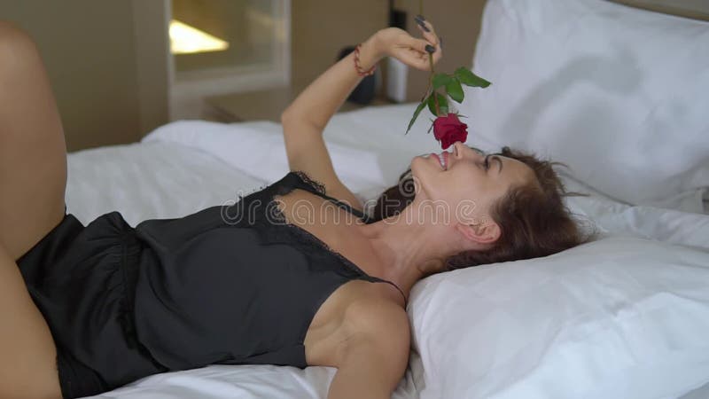 Jeune femme avec des poses joyeuses d'expression dans les sous-vêtements dans le lit blanc de la chambre d'hôtel banque de vidéos
