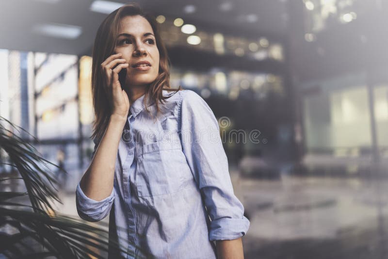 Jeune femme avec du charme d'affaires parlant avec l'associé par l'intermédiaire du téléphone portable tout en se tenant au centr photos libres de droits Jeune femme avec du charme d'affaires parlant avec l'associé par l'intermédiaire du téléphone portable tout en se tenant au centr photos libres de droits
