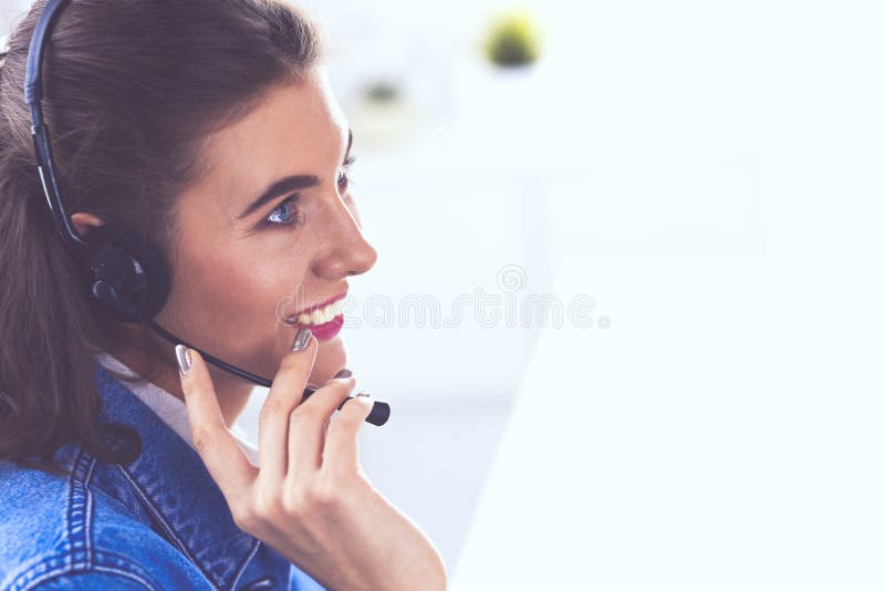 Jeune femme avec du charme heureuse s'asseyant et travaillant avec l'ordinateur portable utilisant le casque dans le bureau photos stock